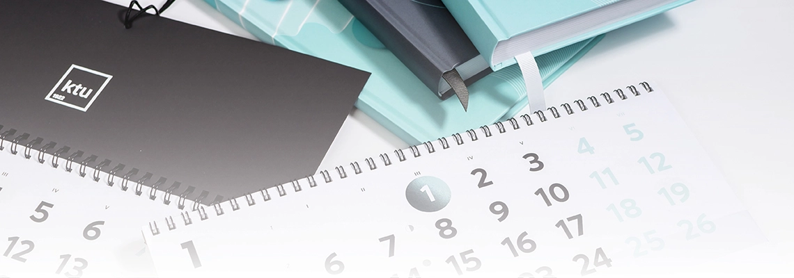 Two calendars and three closed notebooks photographed partially, with only sections of all items visible in the image.